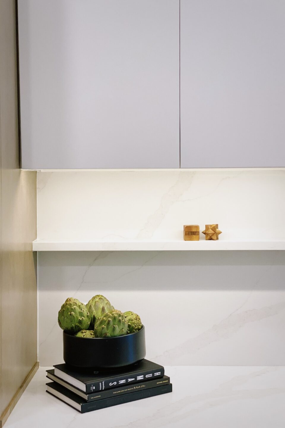 Artichokes In Black Bowl On Stack Of Books In Kitchen