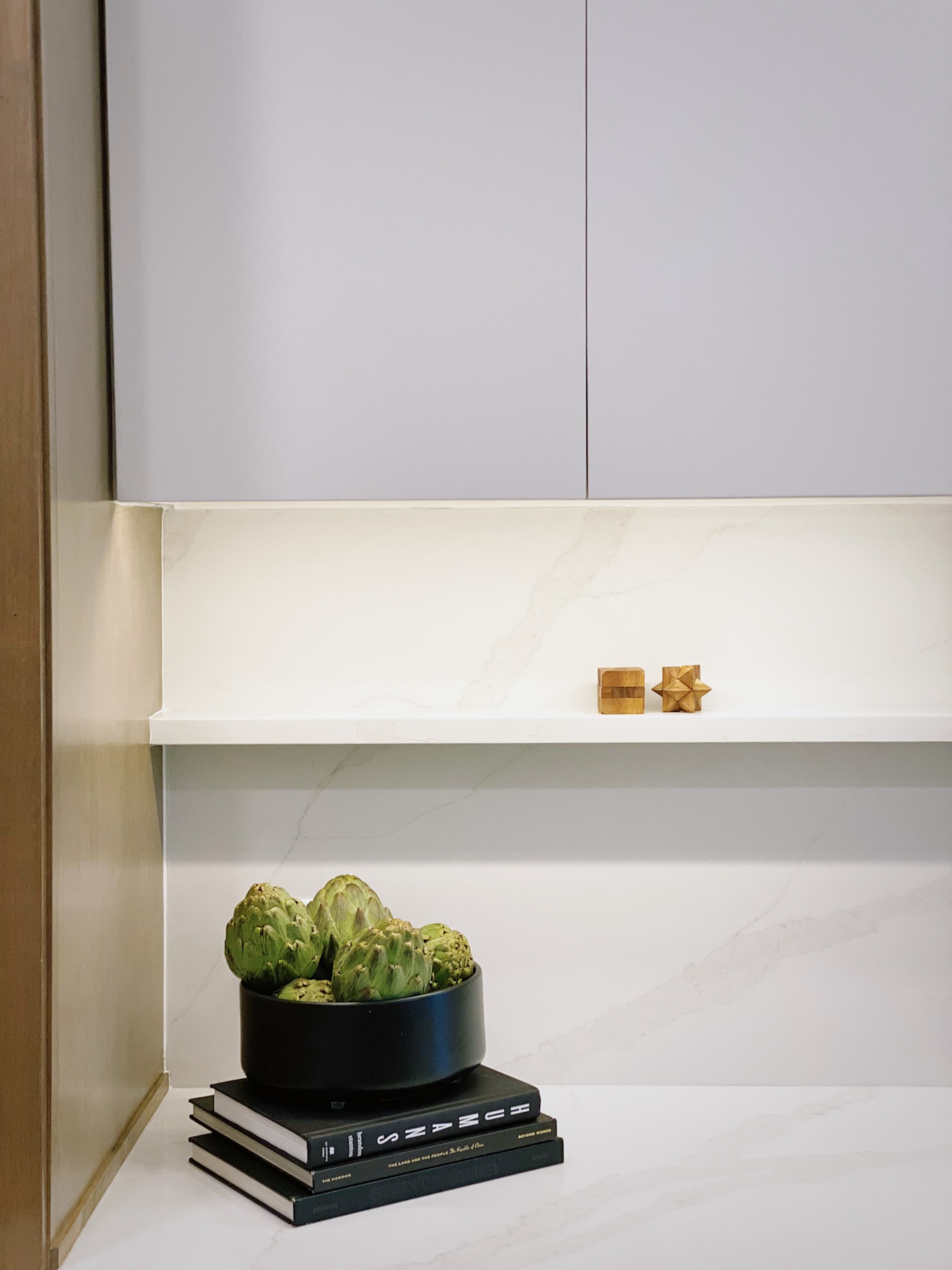Artichokes In Black Bowl On Stack Of Books In Kitchen